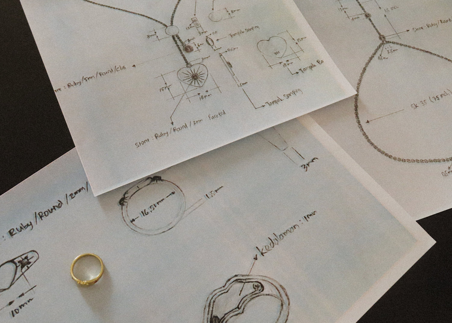 Gold ring on a surface with jewelry design sketches