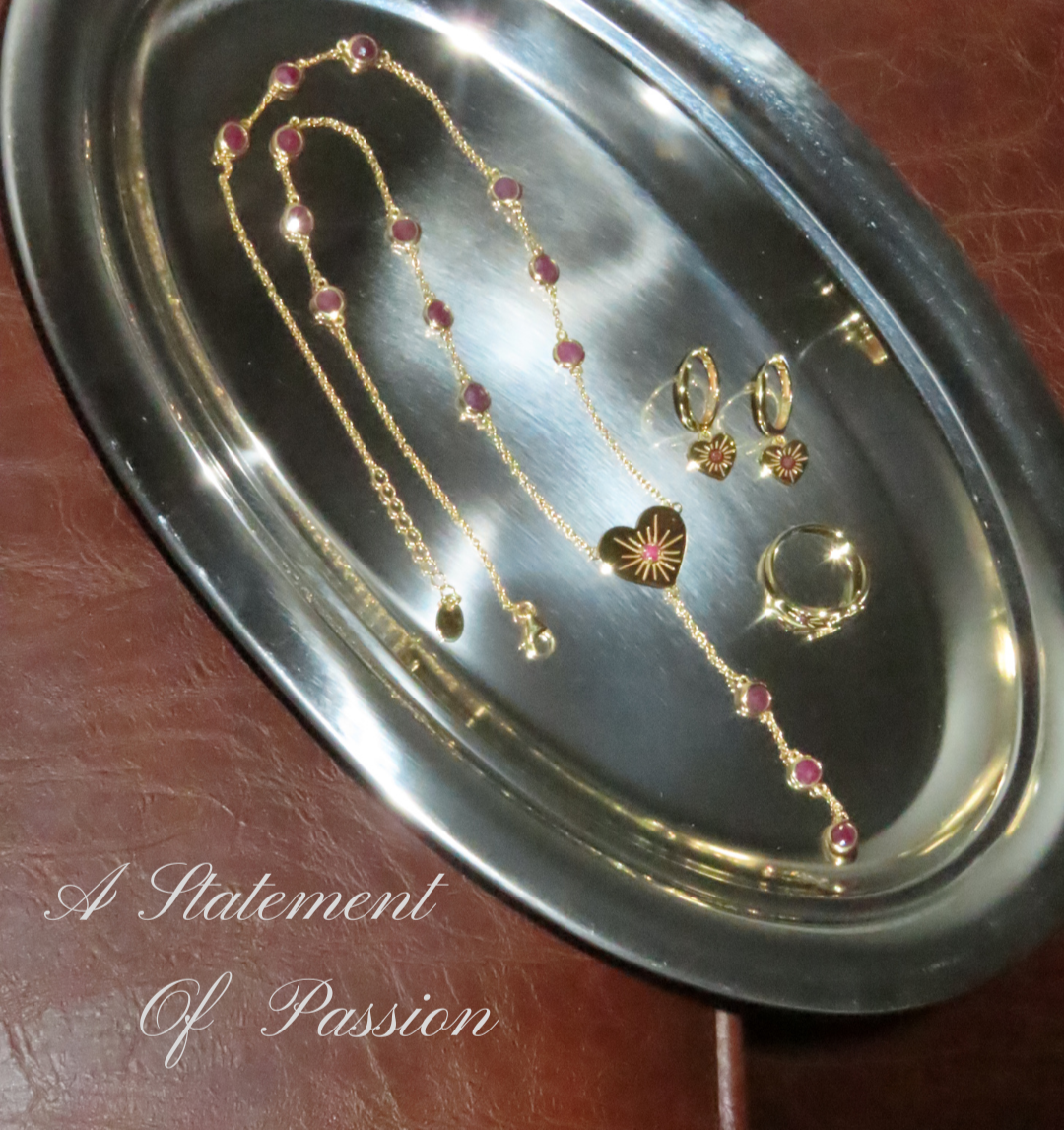 Jewelry set including a necklace and earrings on a metallic tray with 'A Statement Of Passion' text.
